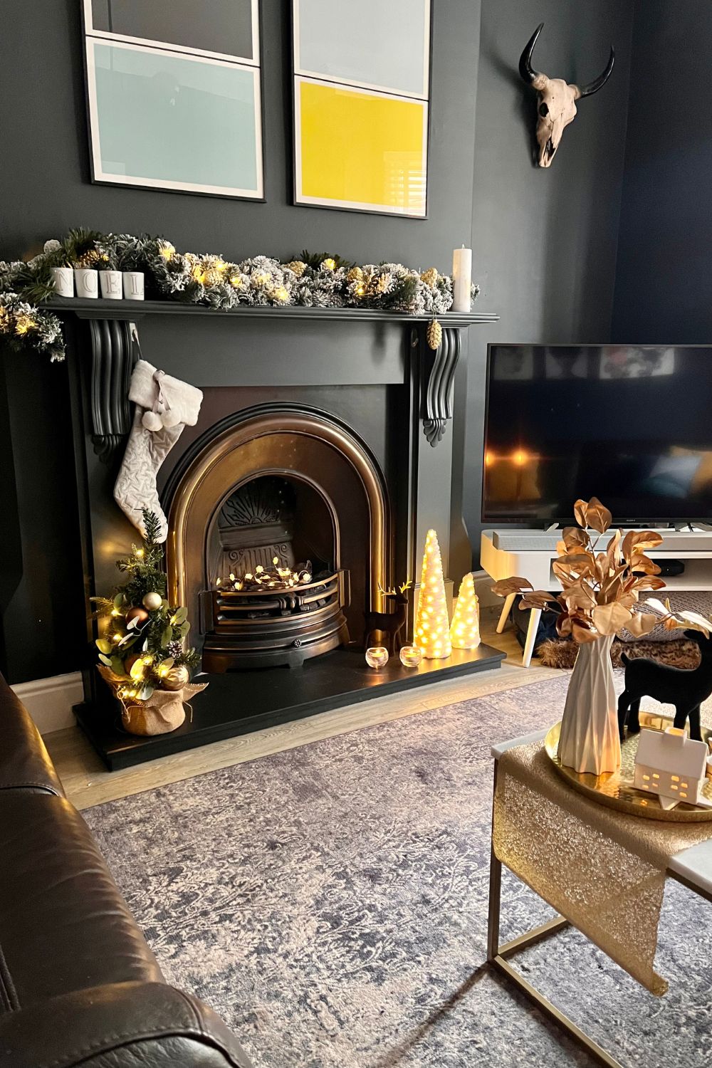 modern living room with dark fireplace and gold christmas styling.