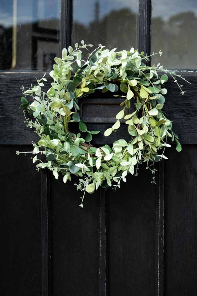 Green wreath on black door, alternative to Christmas tree in a small home