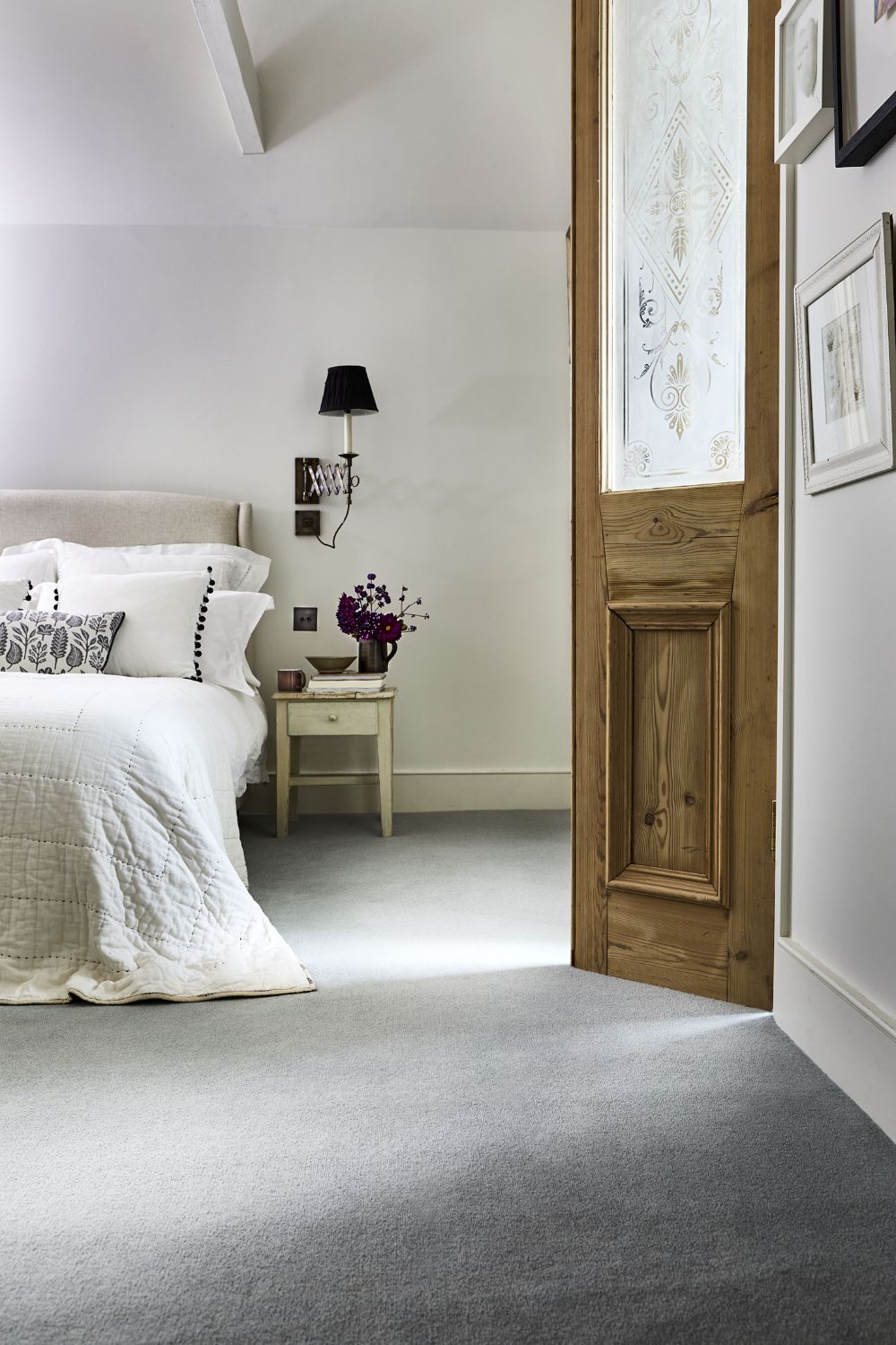 Attic conversion to a spare bedroom, with grey carpet, white walls and white bedding on the double bed