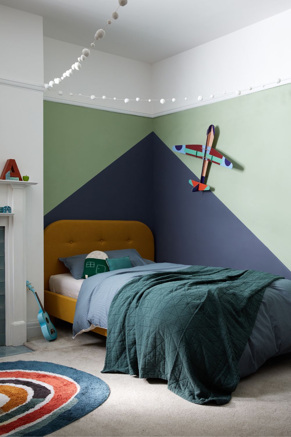 A children's bedroom with colorful walls and a bed, featuring sage green accents.