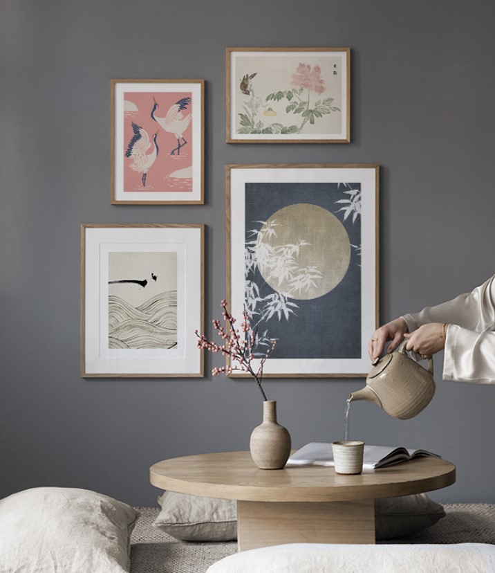 A woman pouring tea on a table in front of Japandi wall art.