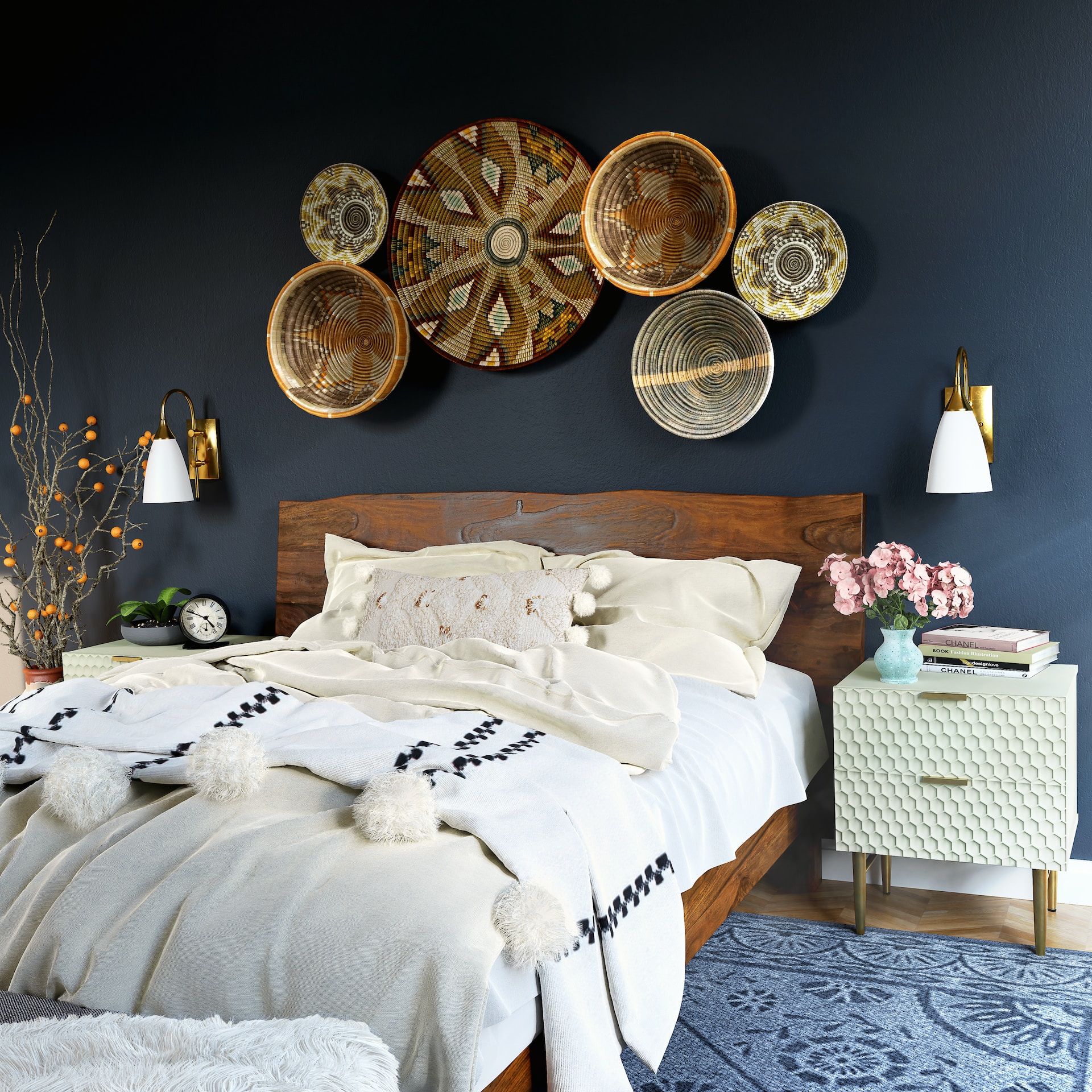 A modern bedroom featuring a dark blue wall adorned with decorative wicker plates, a wooden bed with a luxurious pillow top mattress, and a small mint green nightstand.
