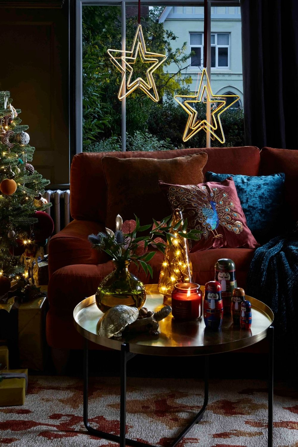 A cozy living room adorned with a magnificent Christmas tree and a vibrant red couch, perfect for exploring enchanting Christmas coffee table ideas.