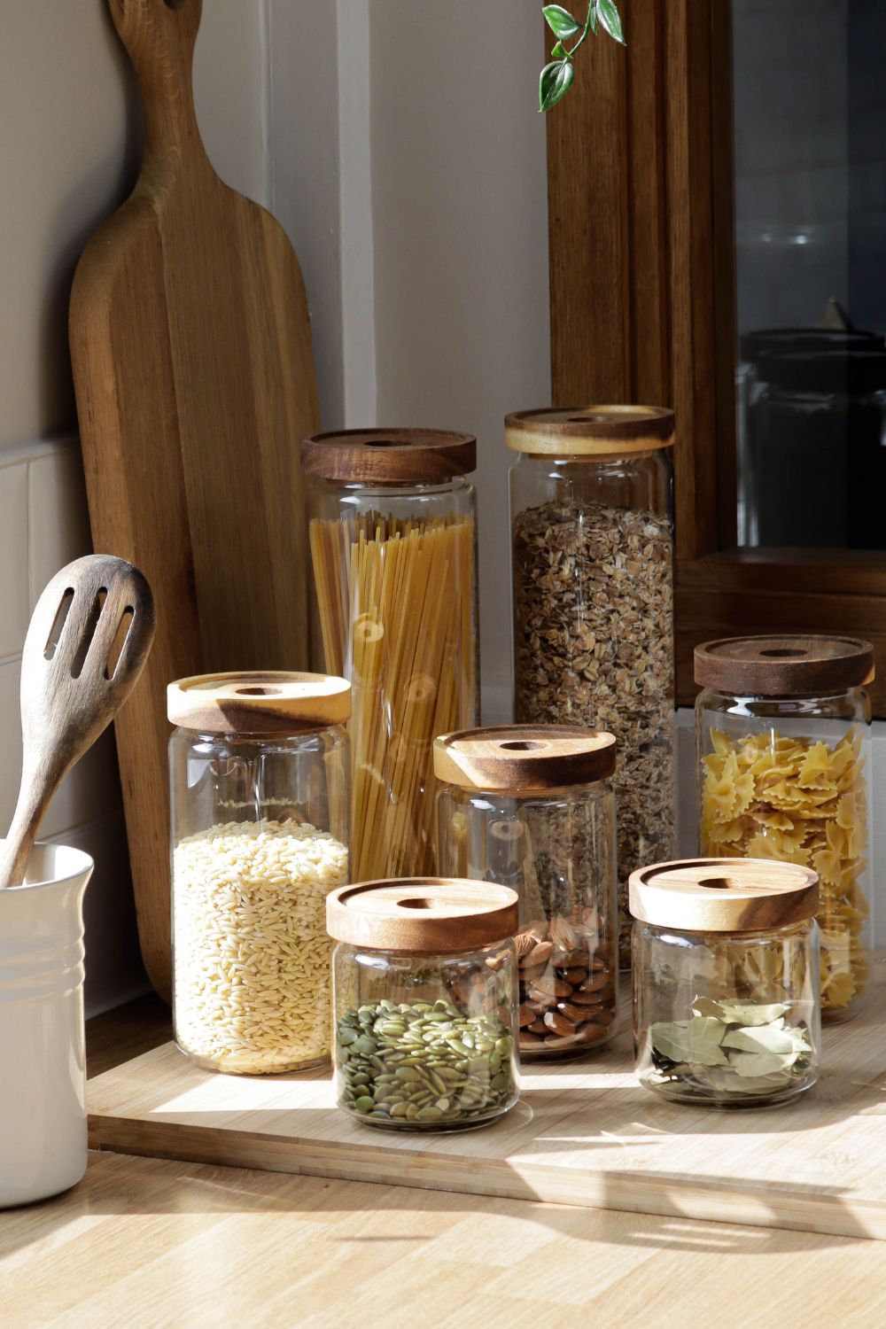 A variety of clear glass storage jarw with wood lids, used for kitchen pantry storage