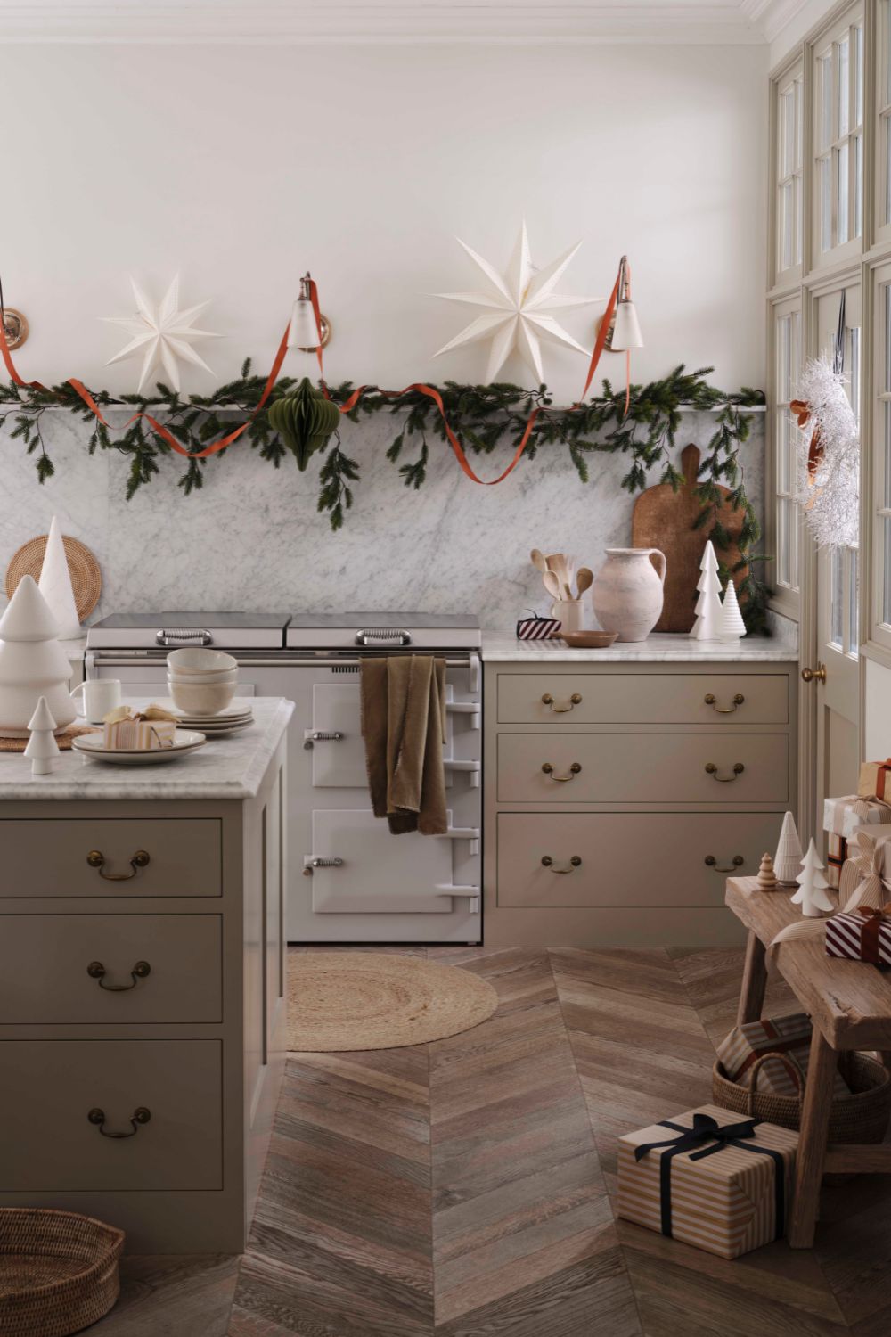 A cozy kitchen prepared for Christmas guests features marble countertops, a traditional stove, and festive ornaments including stars and greenery.