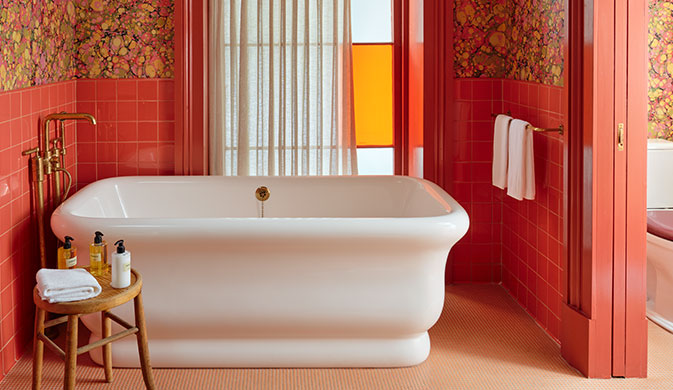 A bathtub in a bathroom with vibrant red walls.