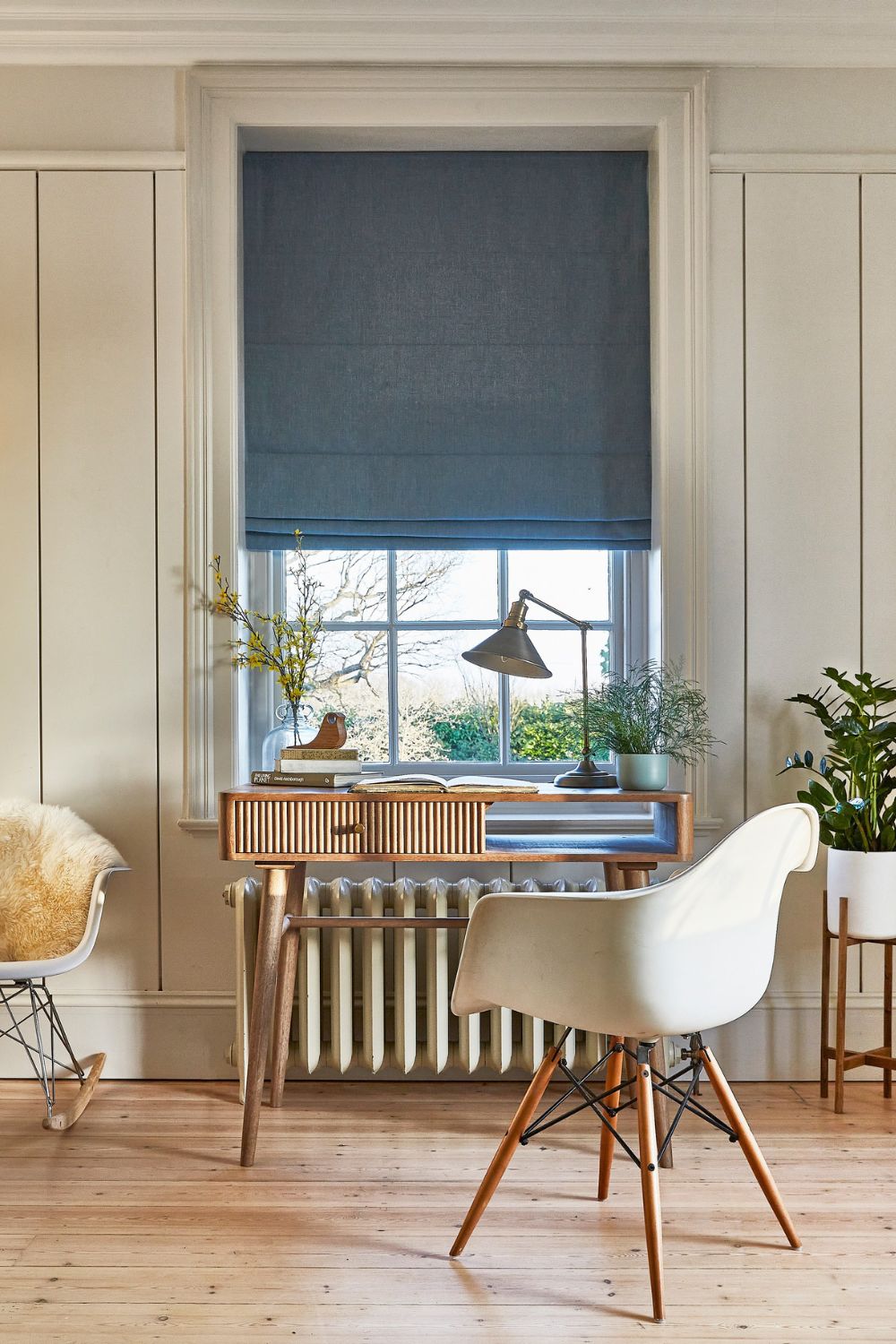A productive home office with a window and a rocking chair.