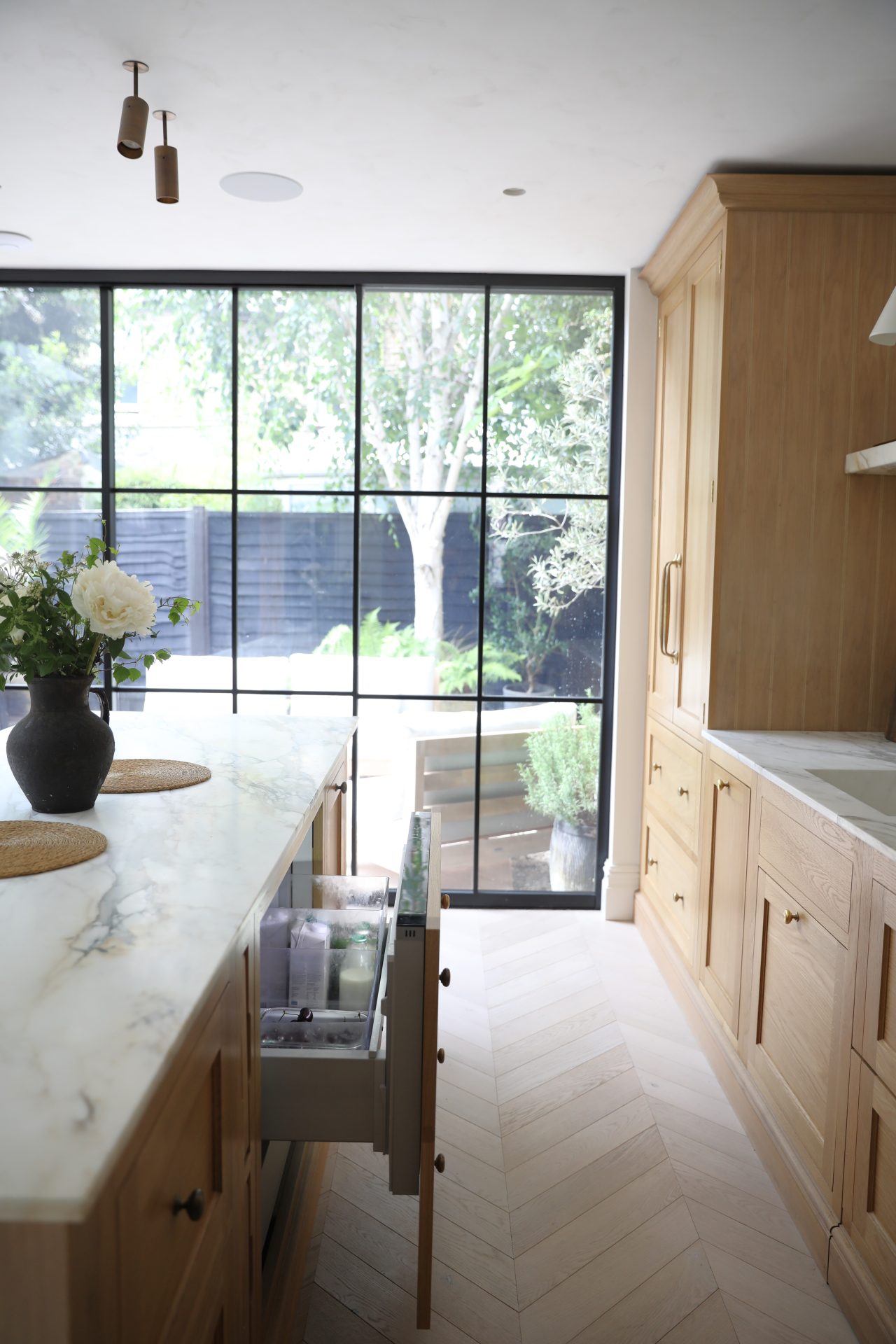 A kitchen with wooden cabinets and a large window featuring laminate flooring expertly installed.