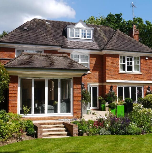 A large red brick house with noise-cancelling windows and a green lawn.