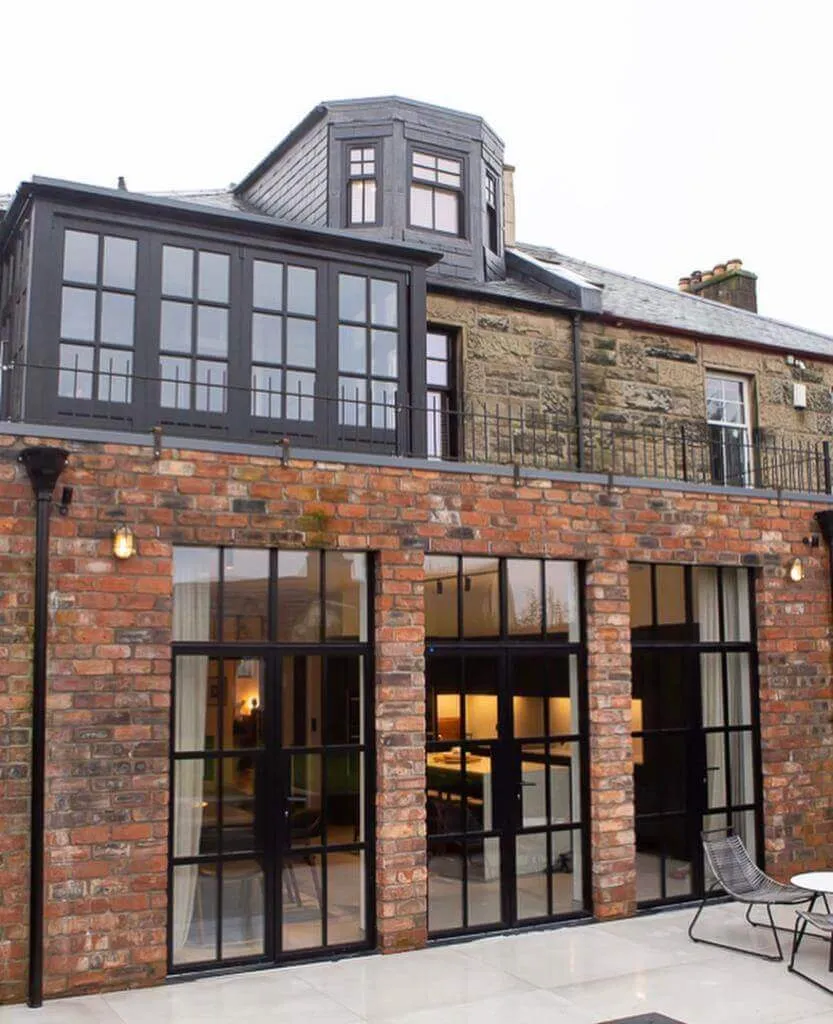 A large brick house with a patio and Crittall style alitherm doors.