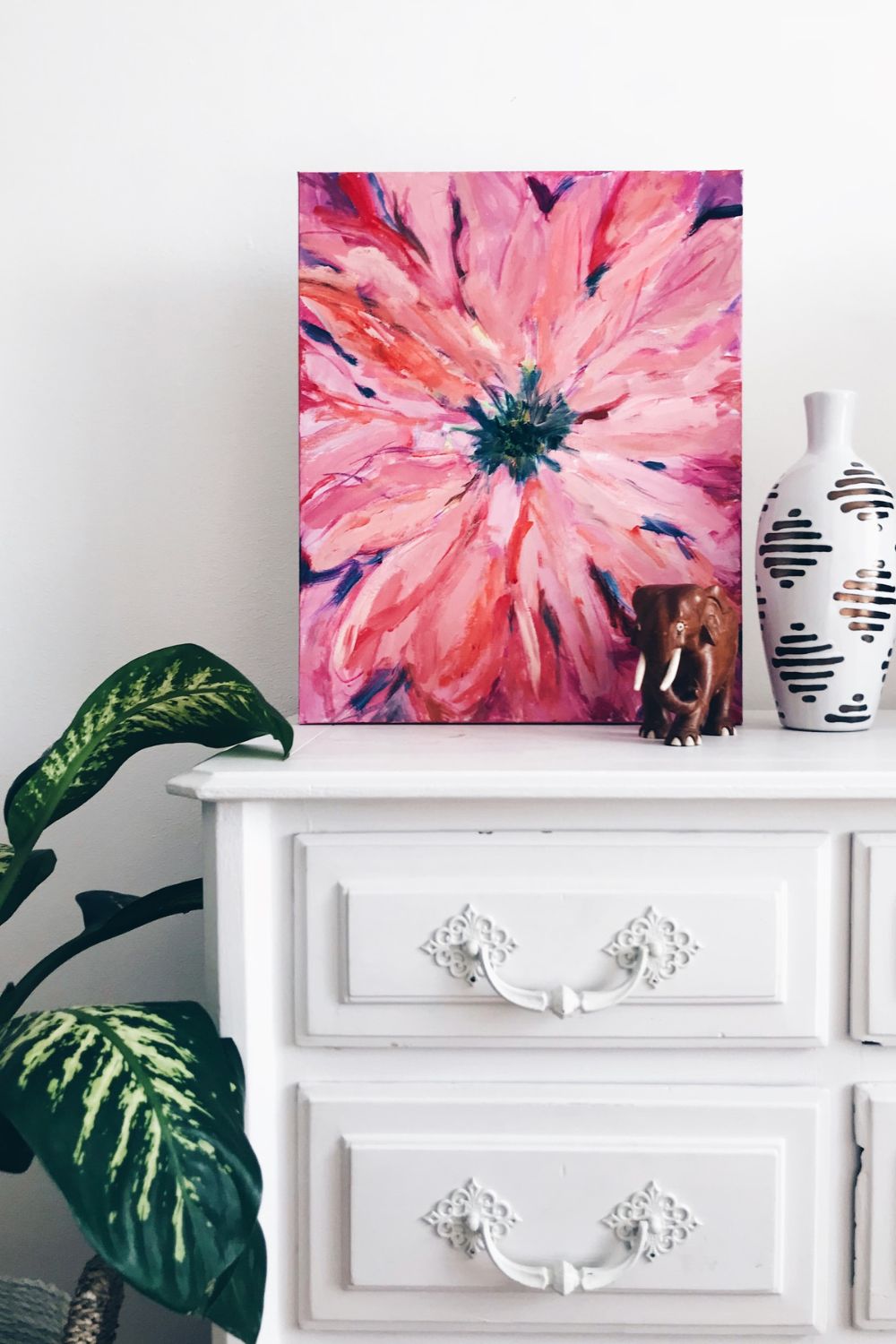 An acrylic photo print of a pink flower on a dresser, perfect for home usage.