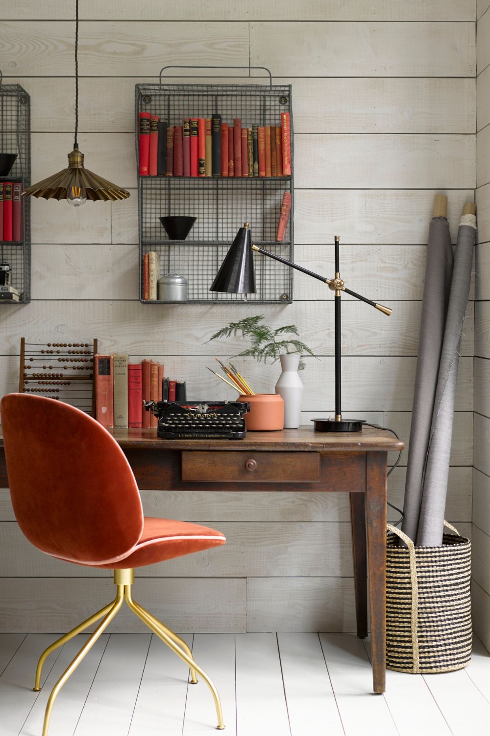 A home office with an orange chair and bookshelves, designed for good posture according to the Home Worker's Guide in 2024.