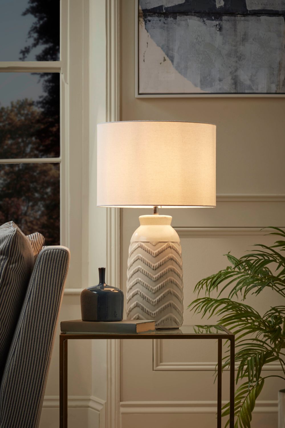 A rental property with a lamp on a table, adding aesthetic decor to the room while placed in front of a window.