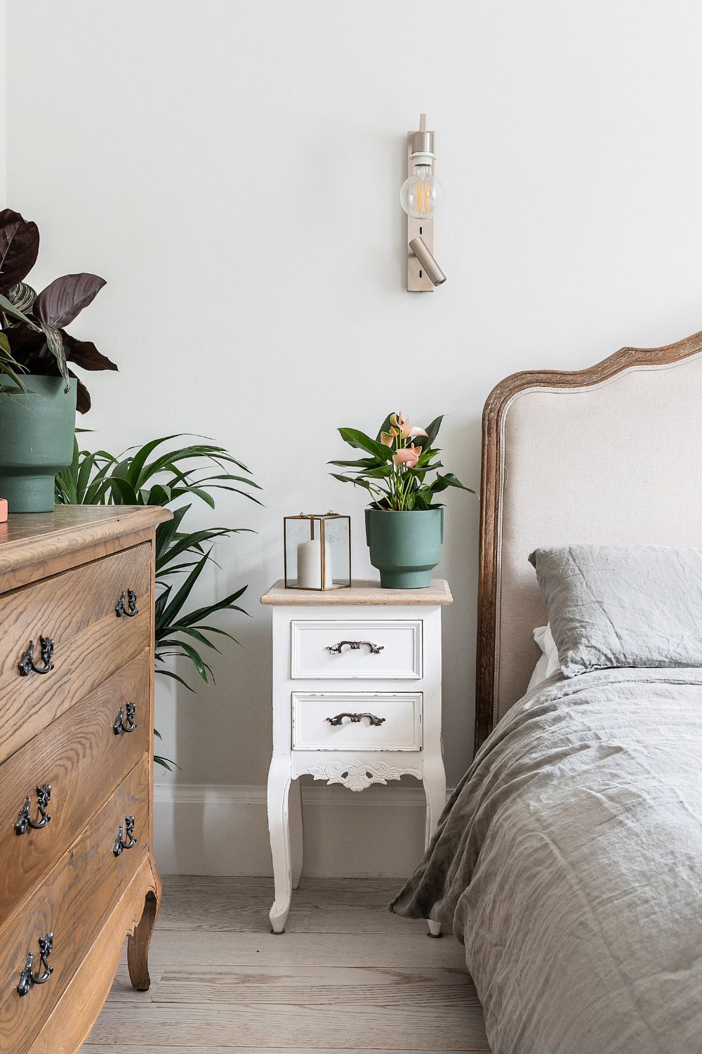 An upgraded bedroom with a bed, dresser and a potted plant.