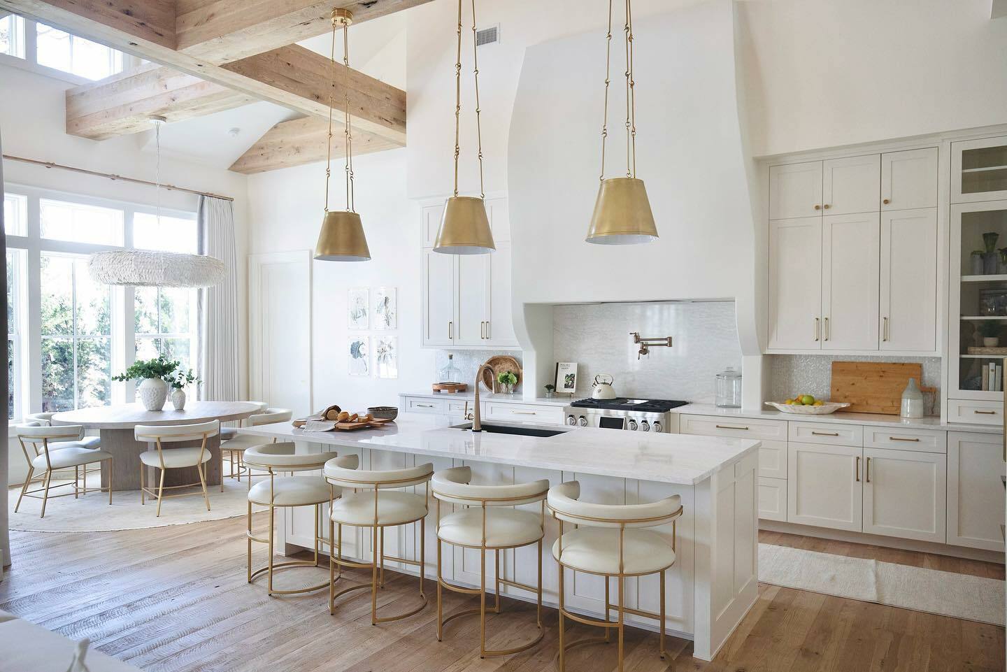 A white kitchen with wooden beams and stools, popular for its clean aesthetic and neutral paint color.