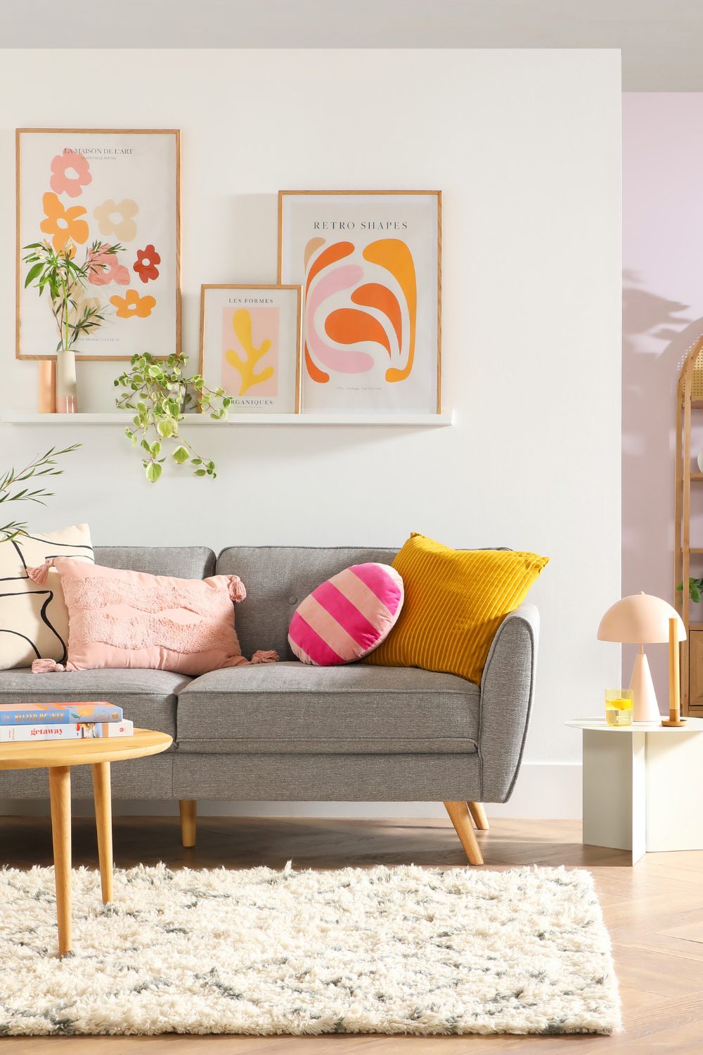 A cozy living room featuring a grey couch and pink pillows.