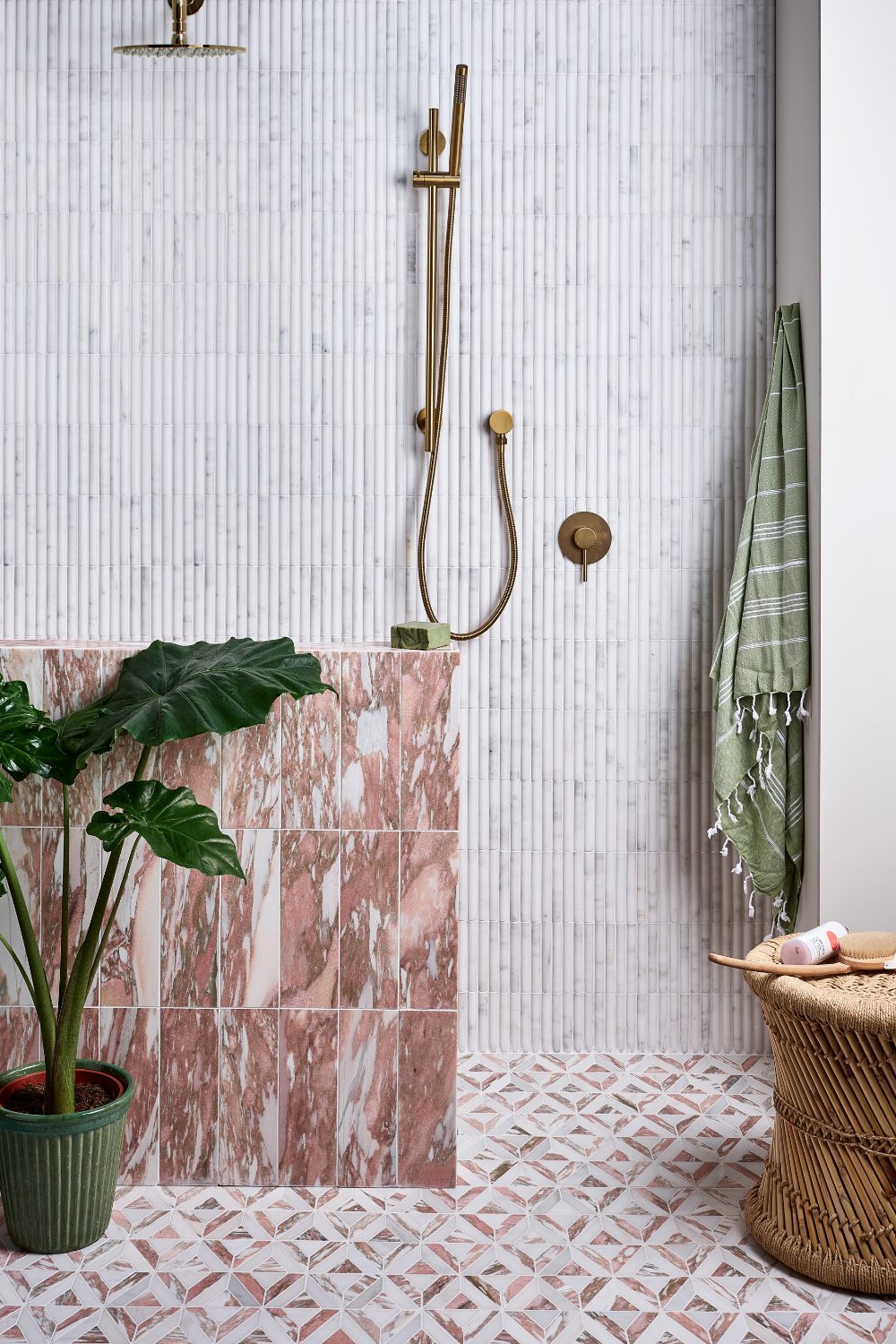 Discover wet room ideas that combine the perfect shower space with a touch of nature, exemplified by a bathroom featuring a pink tiled shower and a vibrant potted plant.