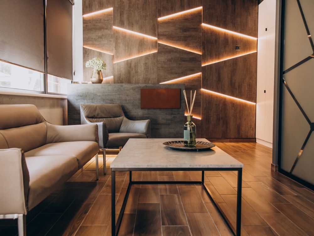 Modern living room with wooden flooring, geometric lighting, and minimalist furniture designed by expert builders.