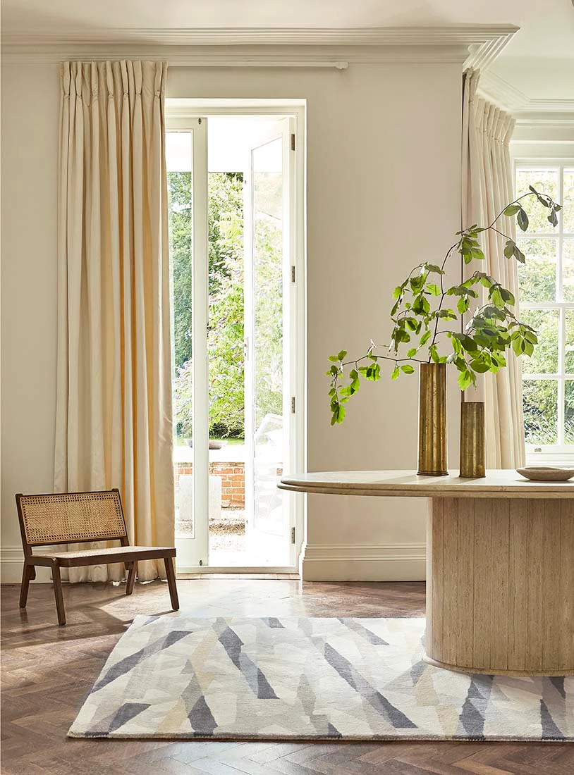 A dining room with a wooden table, chairs, and a perfectly selected rug.