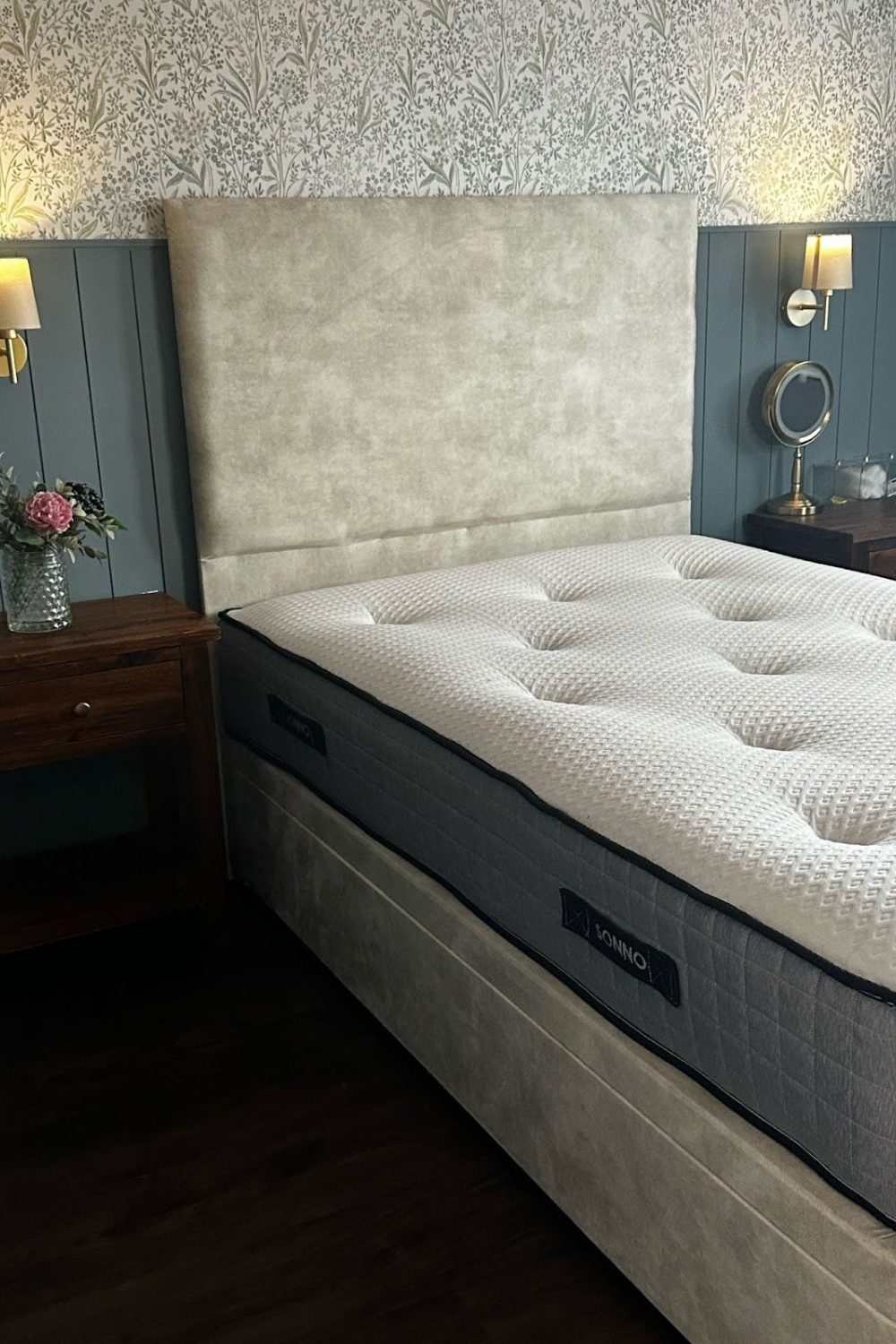 Modern bedroom with a single ottoman bed, patterned wallpaper, and elegant bedside furnishings.