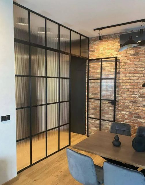 A room with a brick wall and affordable Crittall glass doors.
