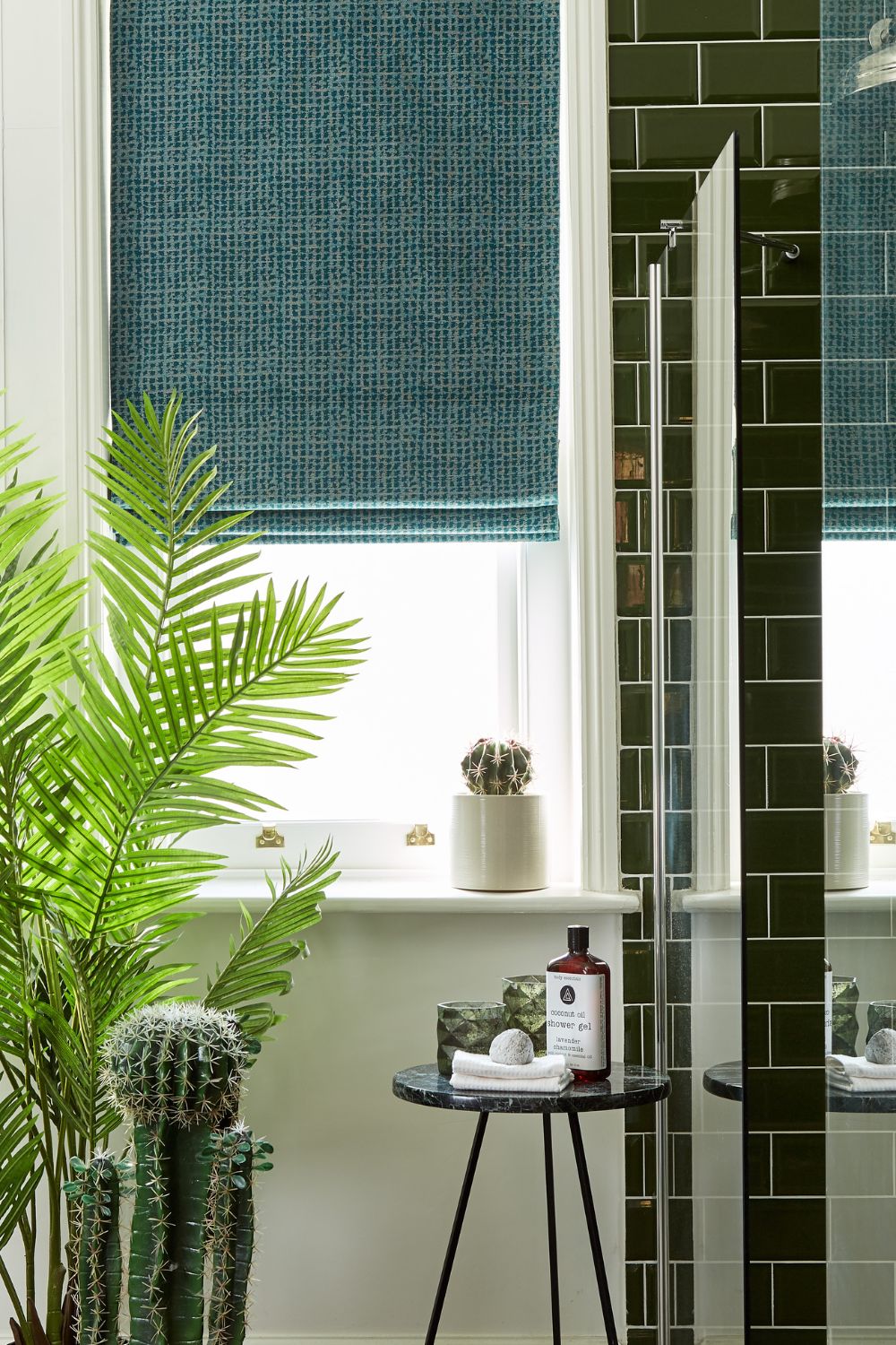 Modern bathroom featuring a glossy green tiled shower, blue patterned blinds, and various potted plants, with a focus on selecting windows for the black side table displaying spa items.