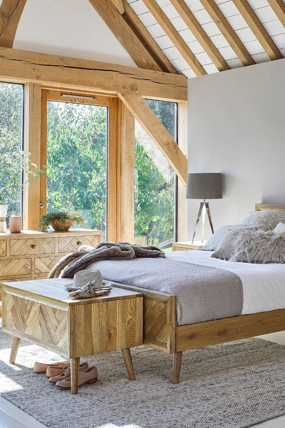 A bright and airy guest bedroom with exposed wooden beams, large windows, and rustic decor is designed to make you feel like home.