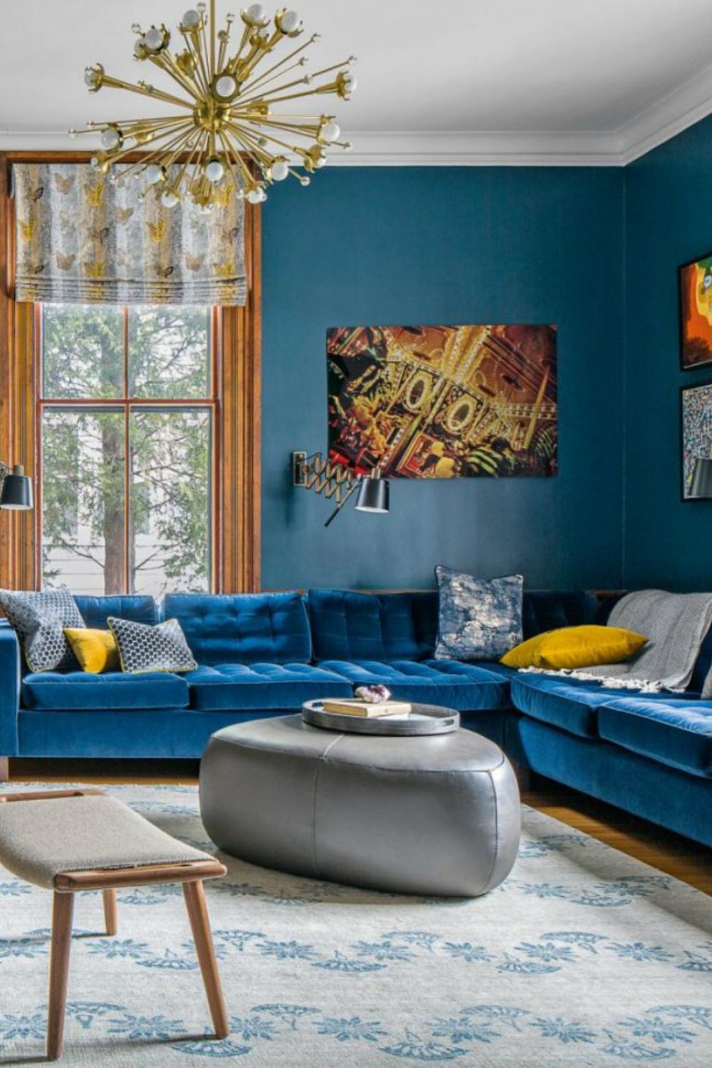 Elegant living room with blue walls, matching sectional sofa with yellow accents, and a modern chandelier that adds value to the house.