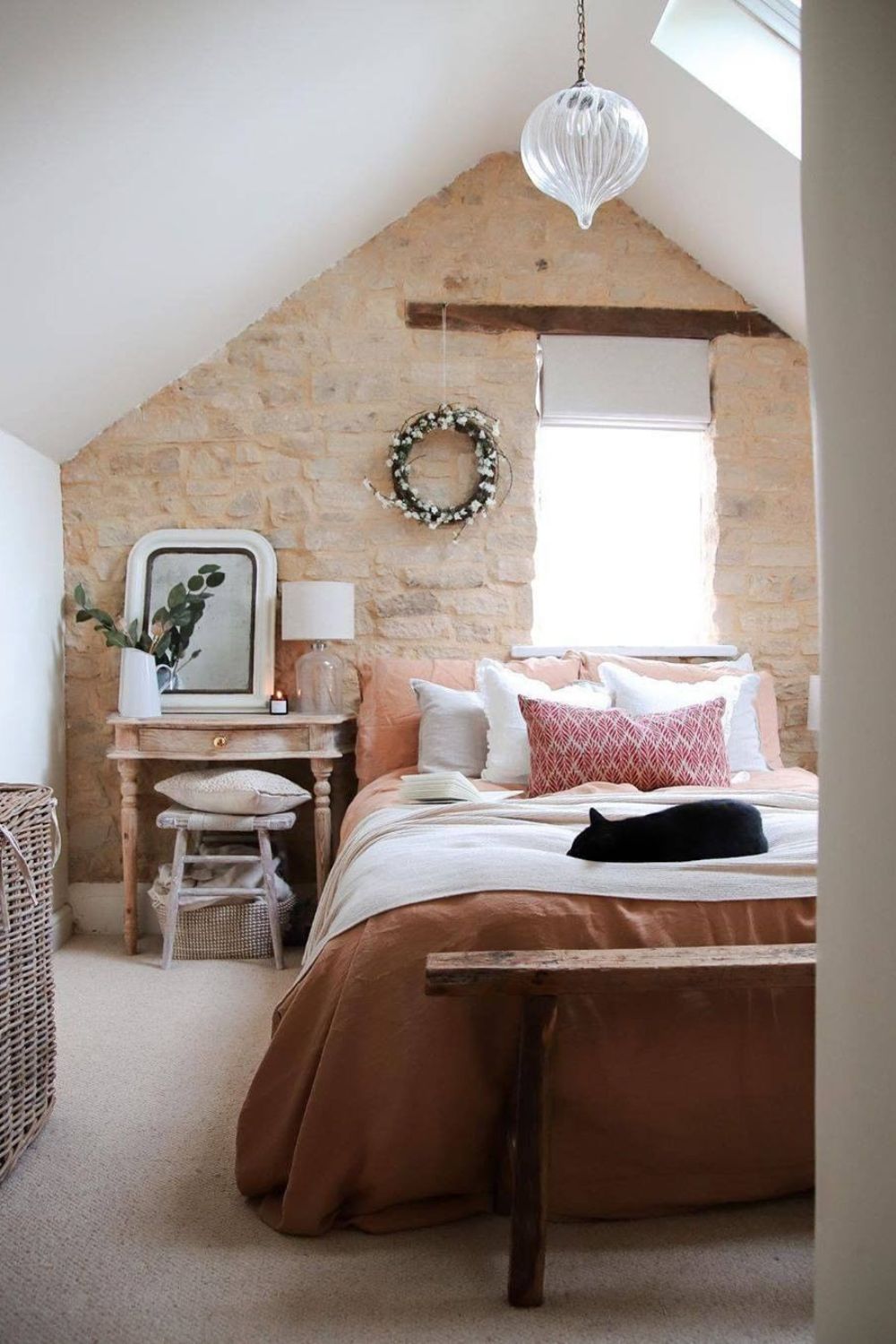 A cozy, rustic bedroom with exposed stone wall, warm-toned bedding, and a pendant light avoids renovation errors to add value to the house.