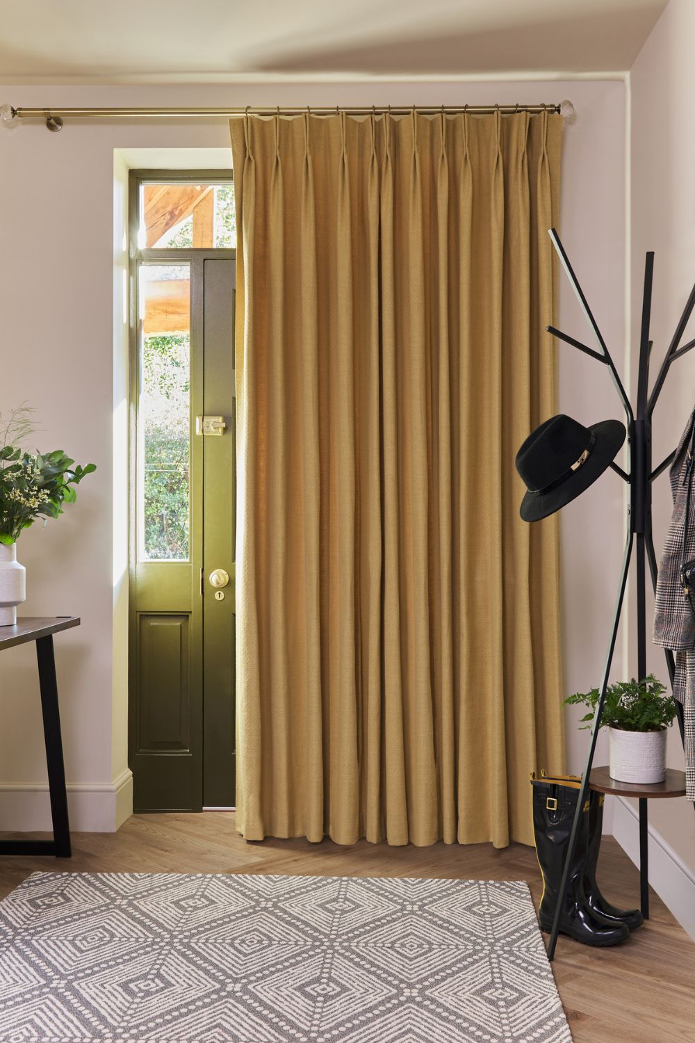 A comprehensive guide to entryway featuring a green security door partially covered by a golden curtain, with a coat rack, rain boots, and plants decorating the space.
