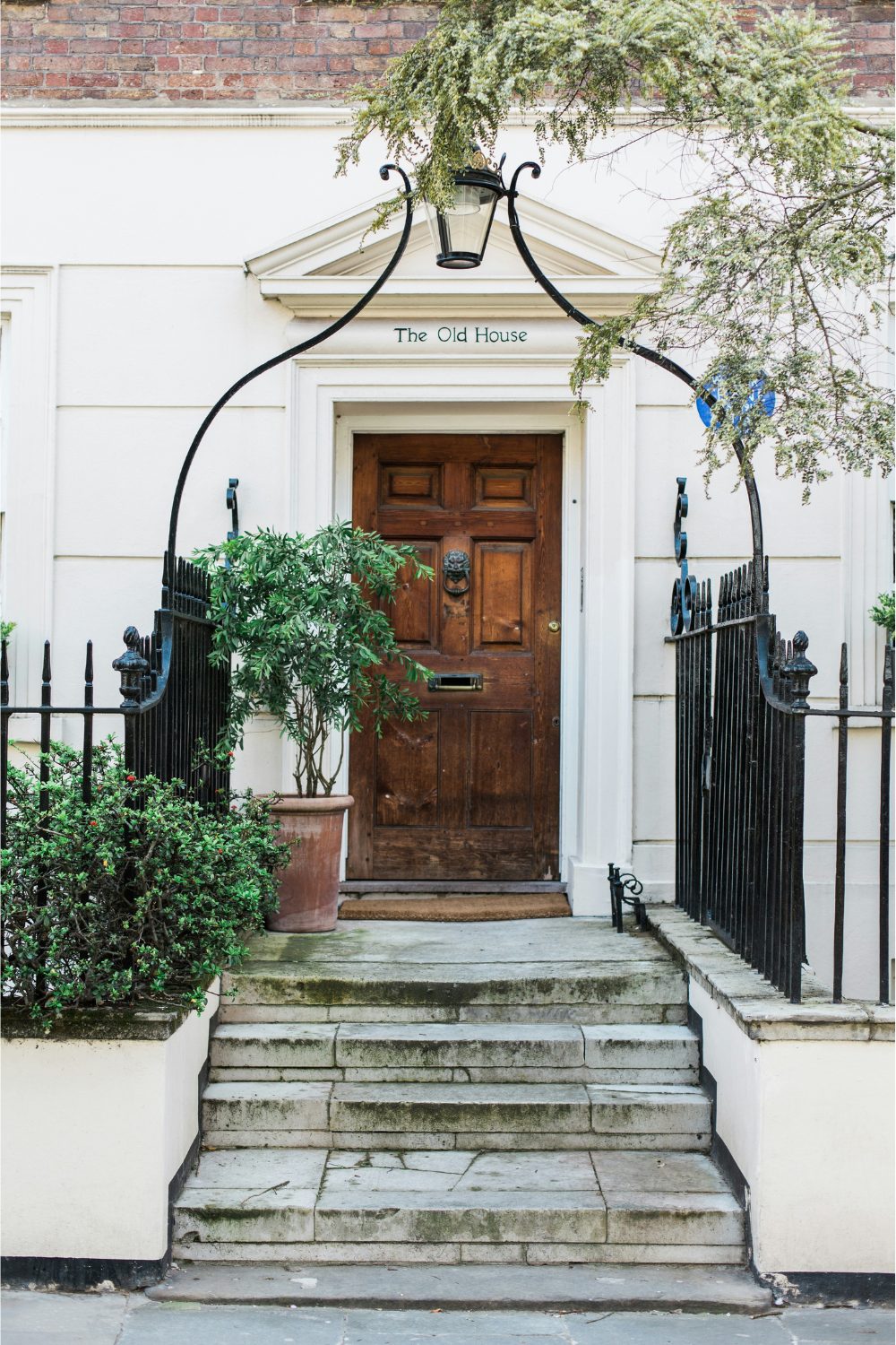 Grand entrance to a white Kensington house with black gate and wooden front door