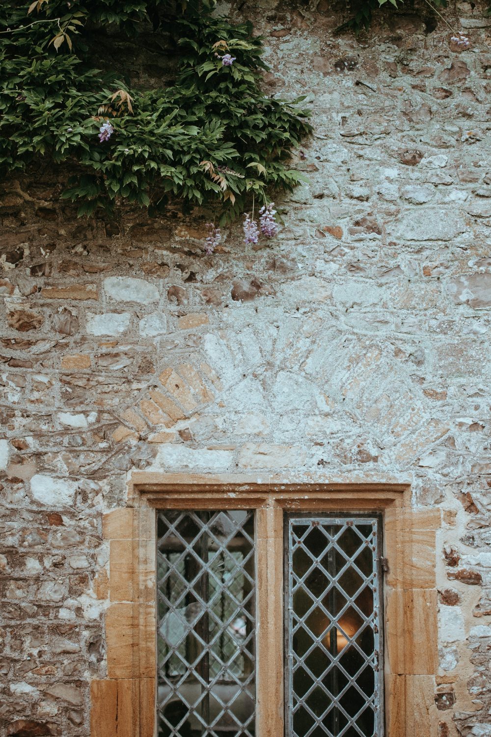 Stone wall with leaded window and tree