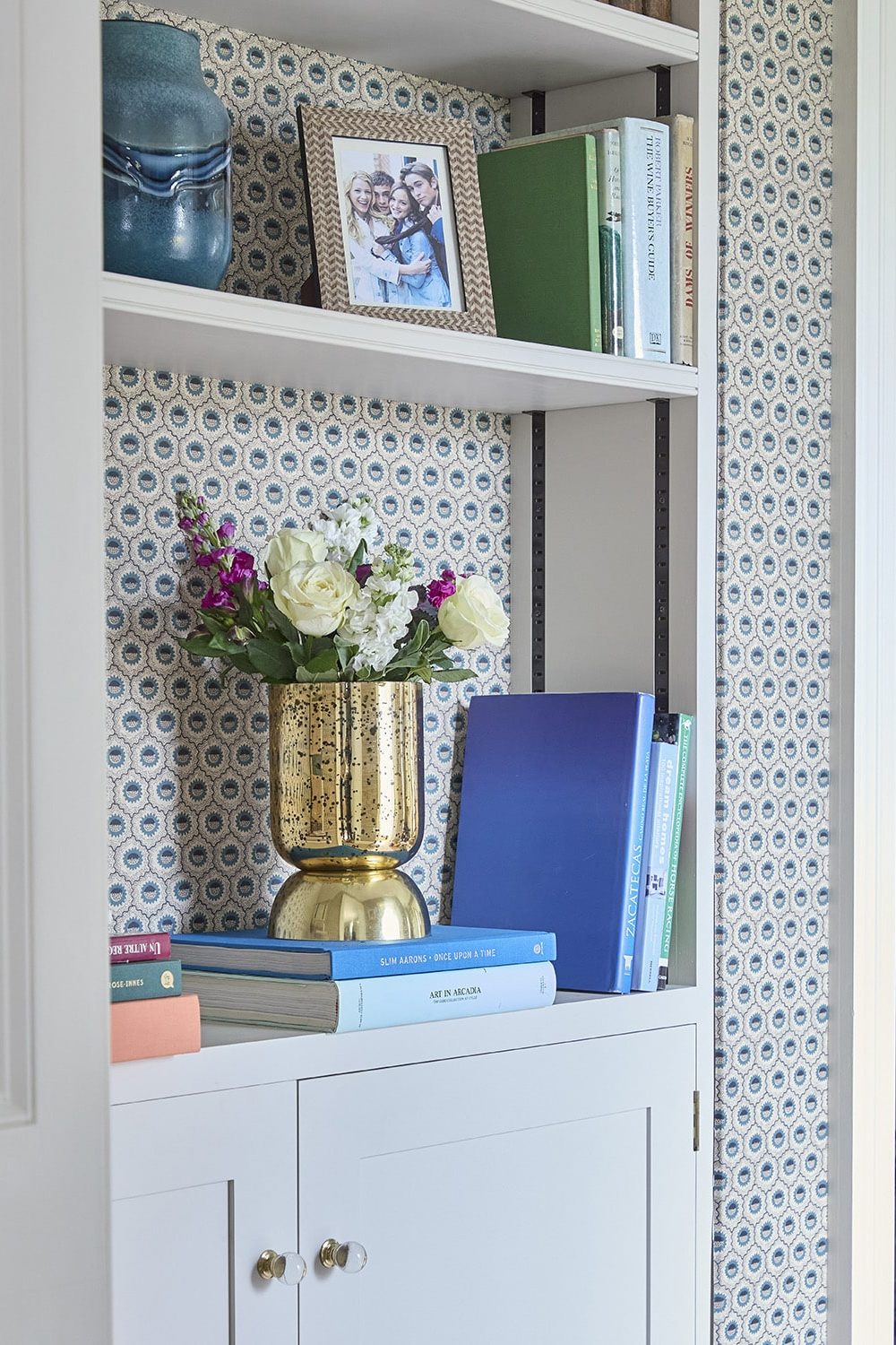bookshelf with gold vase against patterned wallpaper