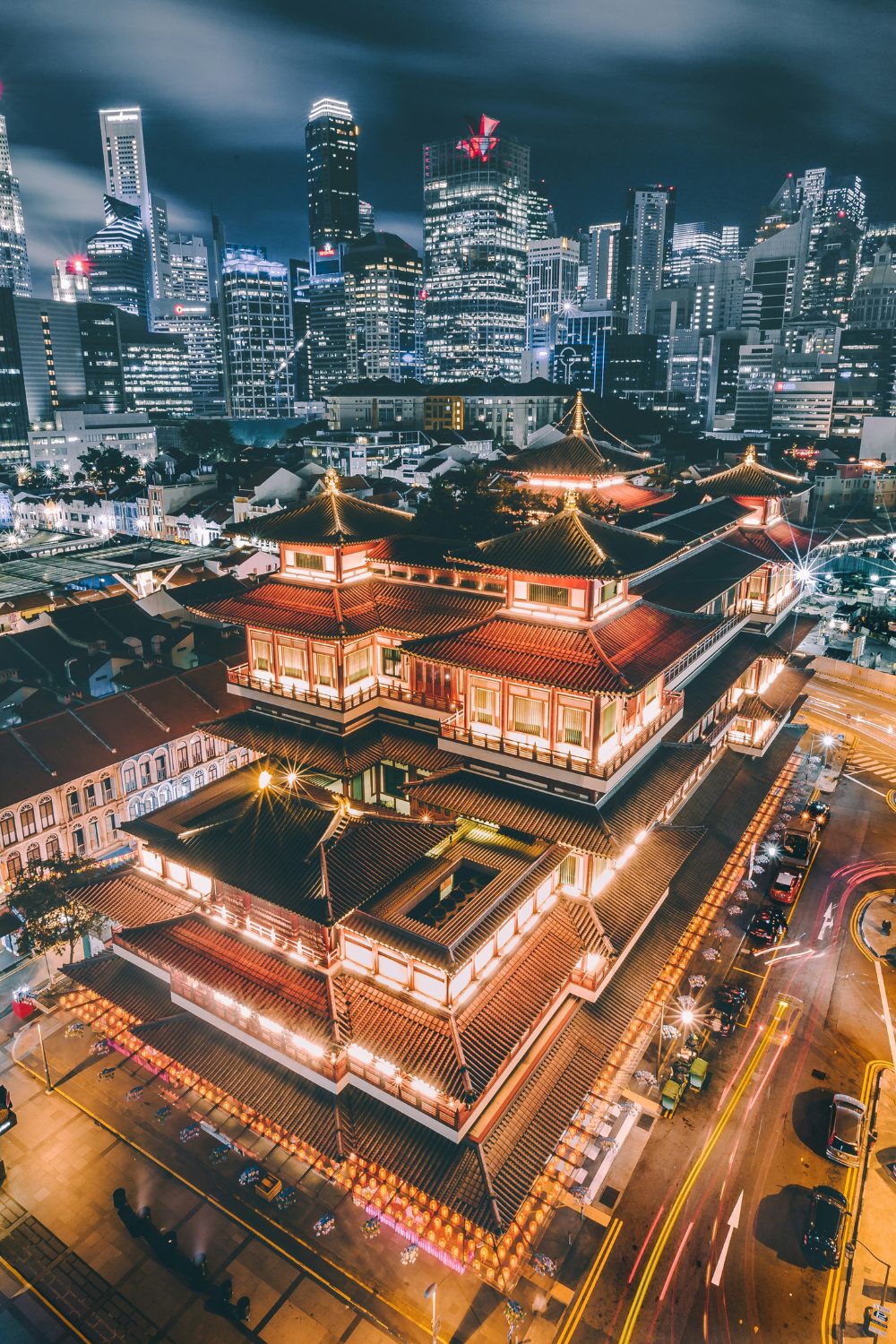 Night skyline of high-rise buildings with a large red temple complex in front