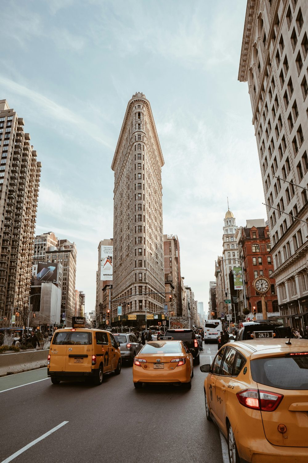 Flatiron building in New York with several yellow taxis