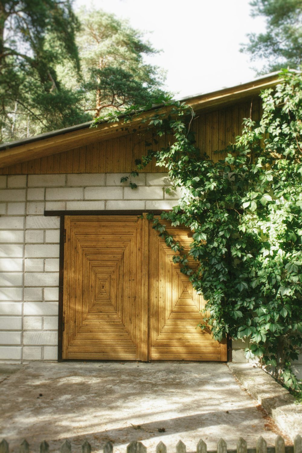 Concrete garage with overgrown ivy and decorative wooden doors