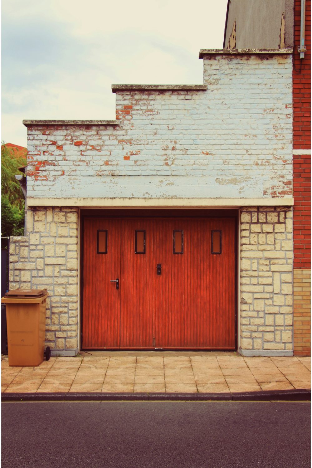 Garage with red wooden door and weathered stepped brick surrounds