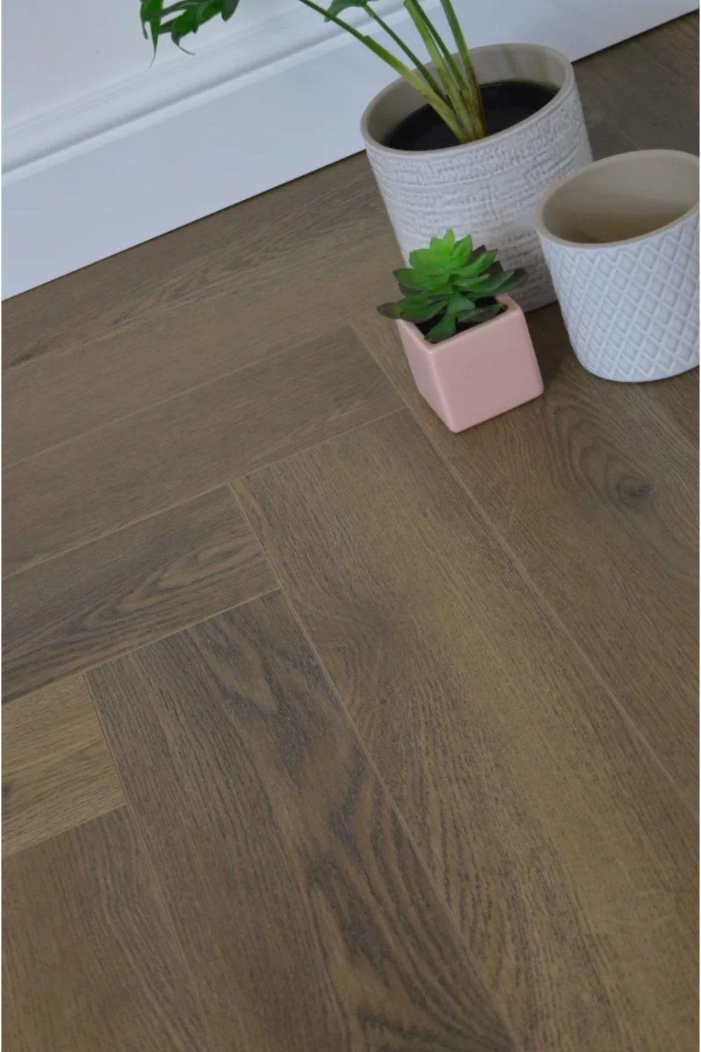 Herringbone-style wooden effect flooring with white plant pots