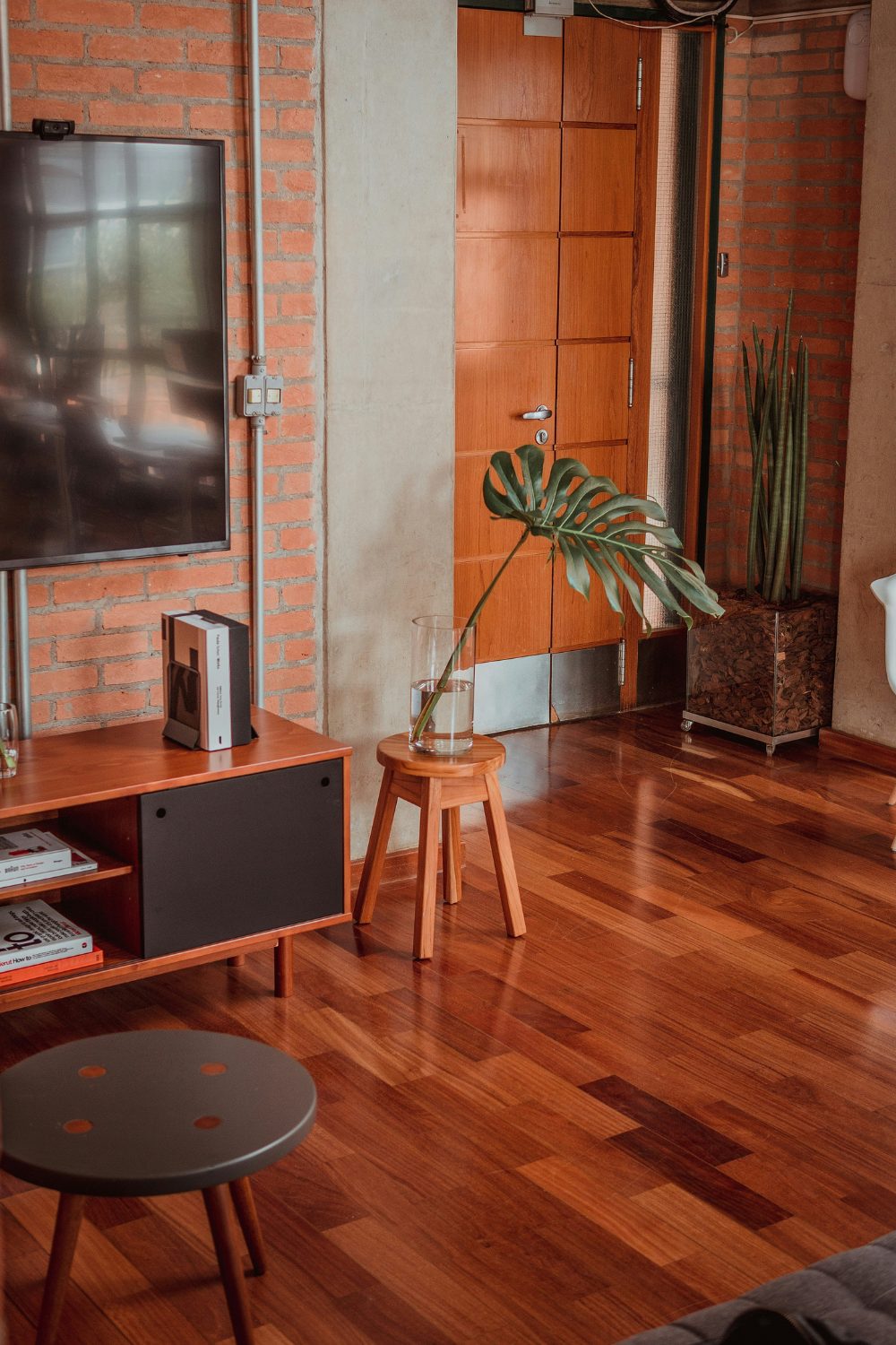 Living room with exposed brick walls, warm wood flooring and plants