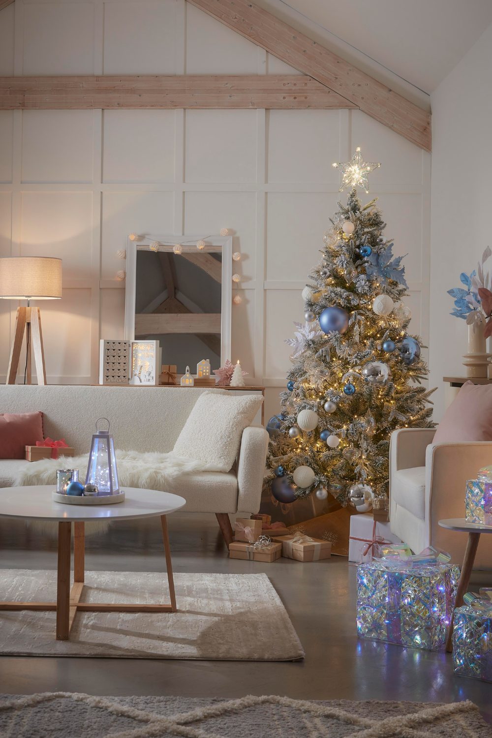 Christmas tree with white and blue ornaments in white living room with high barn walls