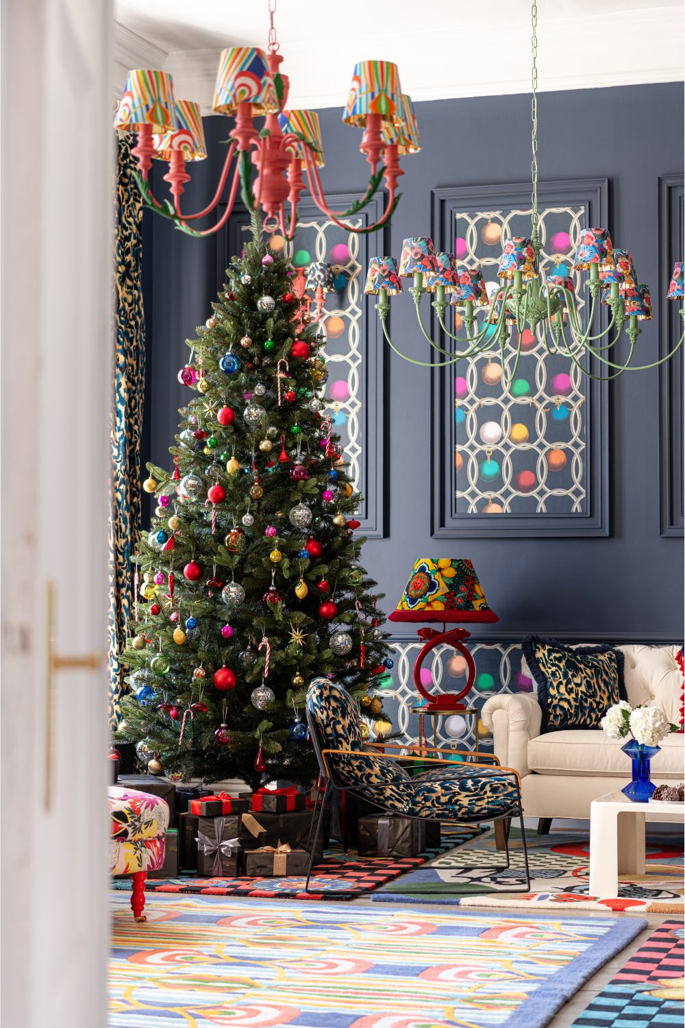 Christmas tree covered with multi-coloured ornaments in bright multi-patterned living room under patterned colourful lamps