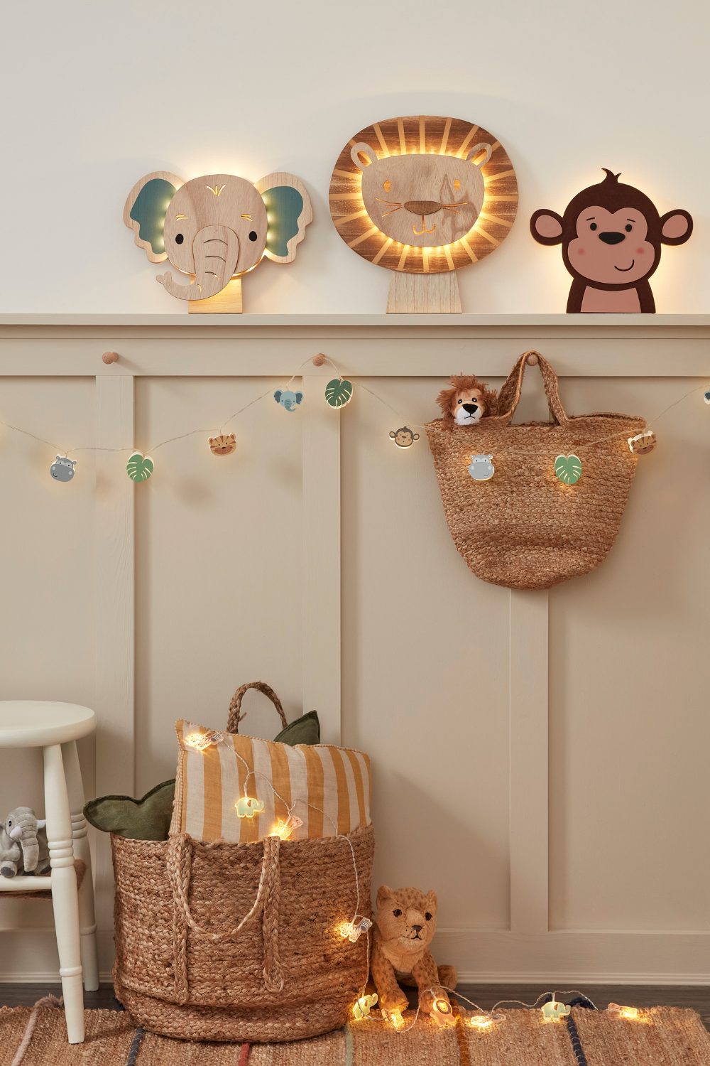 Woven storage baskets hanging from white panelled wall with wooden animal fairy lights and lamps