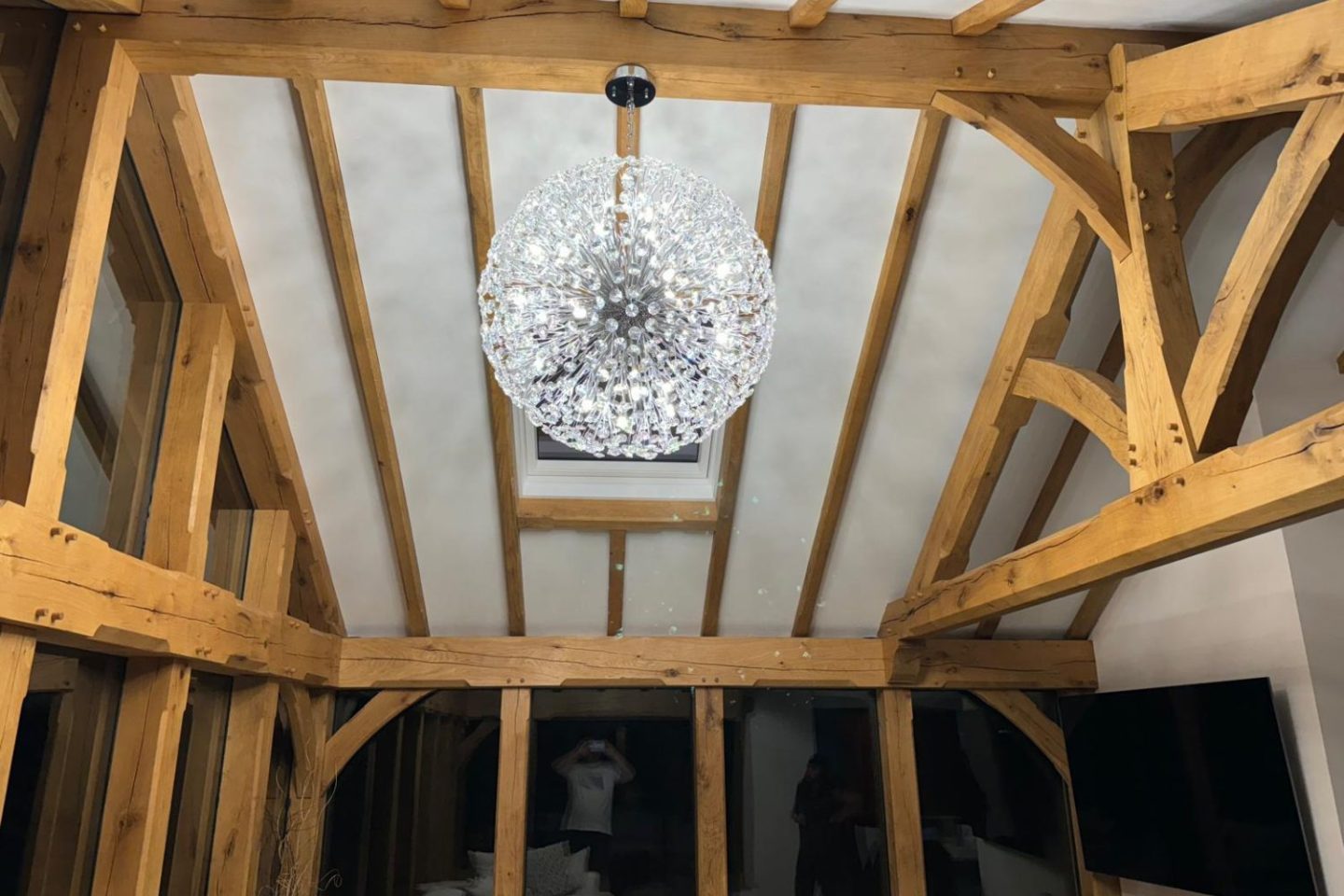 Circular light feature hanging from a beamed barn roof 