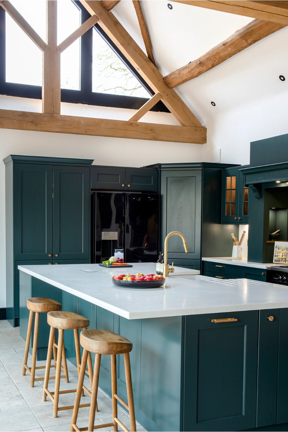 Kitchen with dark cabinets, wood stools and marble island with a high ceiling with exposed beams