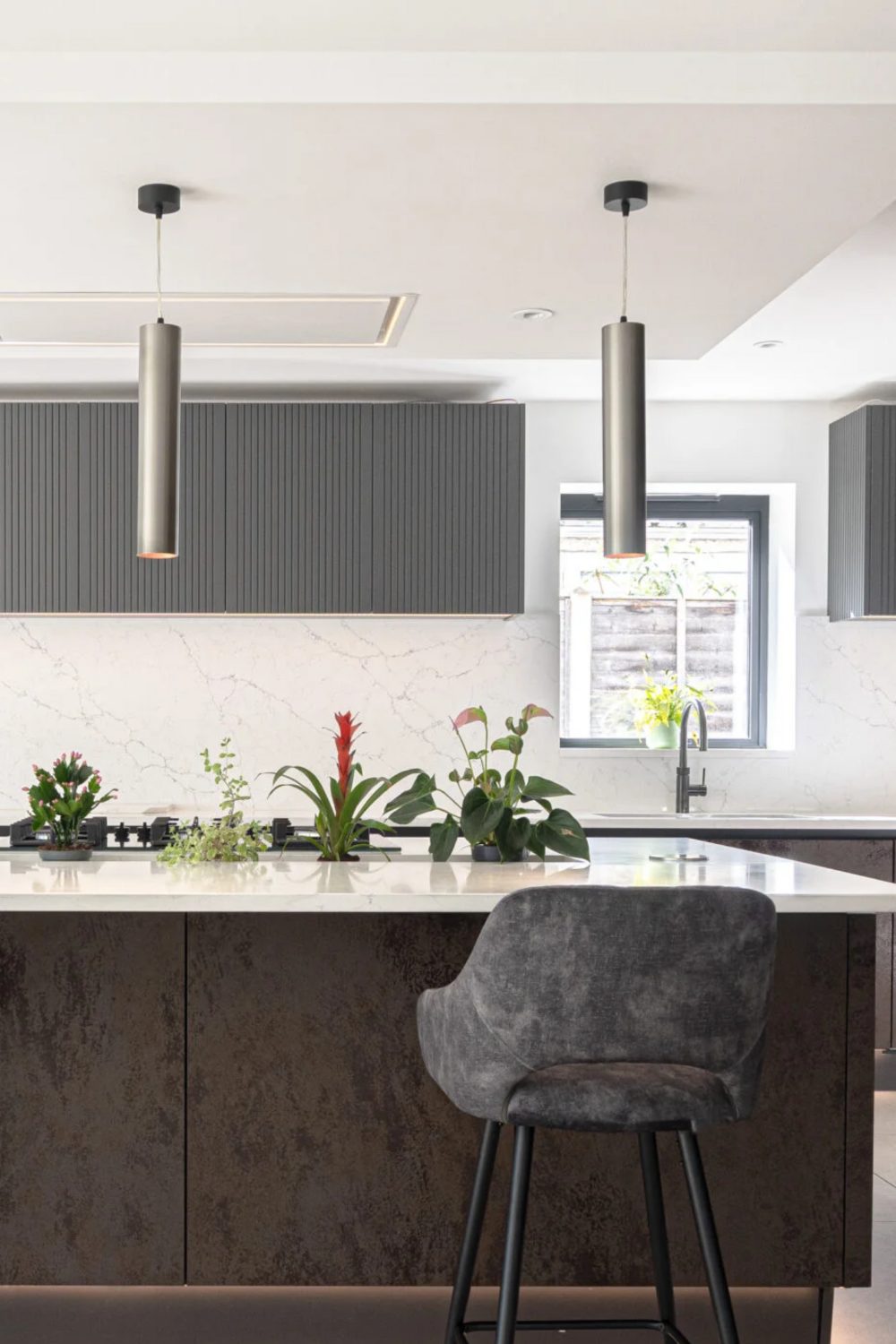 Modern kitchen with black cabinets and white counter with plant feature and black lamps