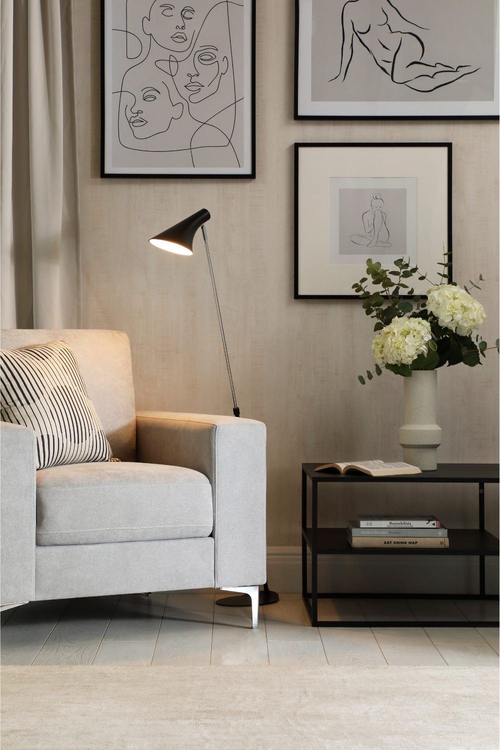 White living room with black and white framed print, black table and lamp