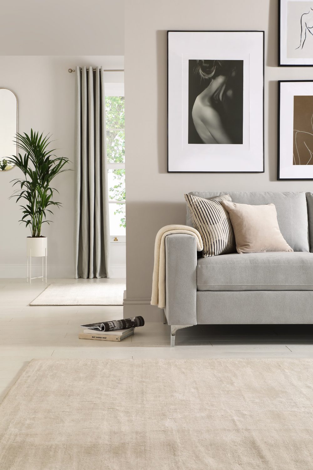 White living room with grey sofa, neutral rug and black and white framed prints