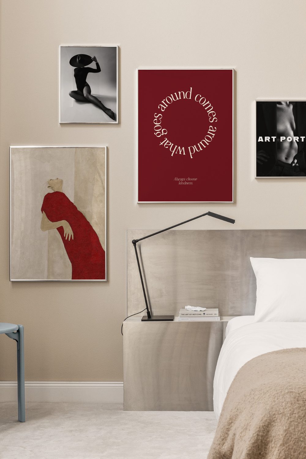White bedroom with grey bed and black lamp in front of red and black prints in gallery wall