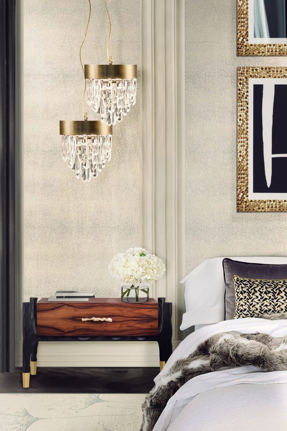 White bedroom with hanging chandelier lamps, gold framed prints, dark wood bedside table and white bed with fur throw