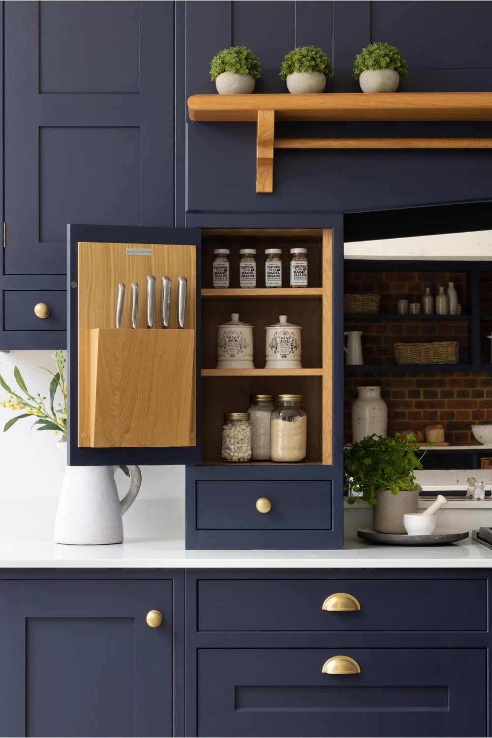 Navy kitchen cabinets with gold handles with spice jars and knife block